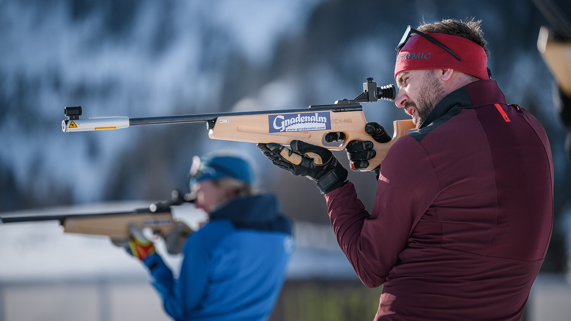 Zwei Personen beim Zielen mit einer Biathlonwaffe vor der Gnadenalm