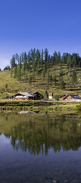 Sommeransicht der Gnadenalm vor einem See in Obertauern
