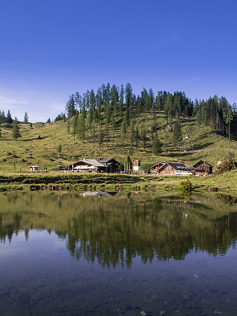 Sommeransicht der Gnadenalm vor einem See in Obertauern