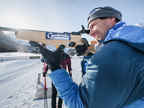 Ein Mann beim Zielen mit einer Biathlonwaffe vor der Gnadenalm