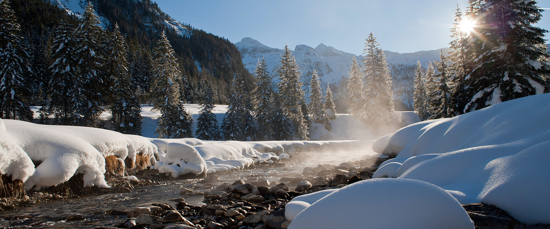 Eine winterliche Landschaft mit einem Bach und Bäumen in Obertauern