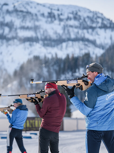 Drei Personen beim Zielen mit einer Biathlonwaffer vor der Gnadenalm