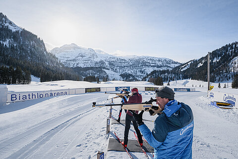 Drei Personen beim Zielen mit einer Biathlonwaffer vor der Gnadenalm